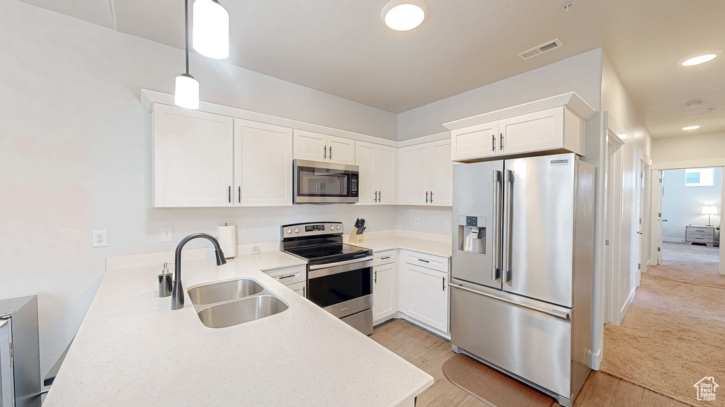 Kitchen with appliances with stainless steel finishes, light wood finished floors, white cabinetry, pendant lighting, and recessed lighting