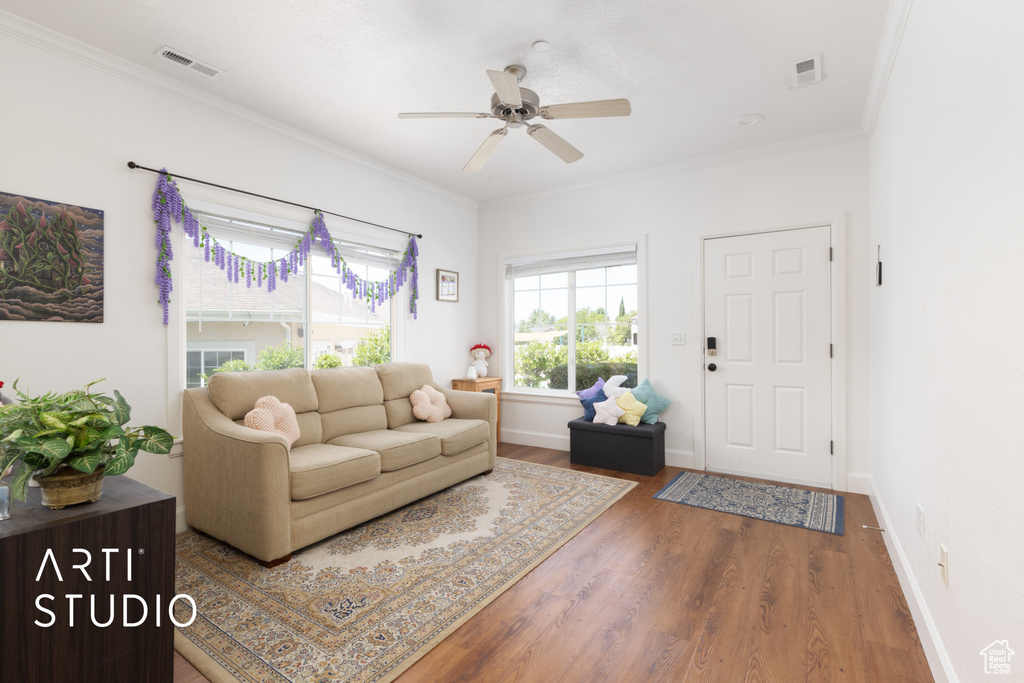Living area featuring wood finished floors, a ceiling fan, and crown molding