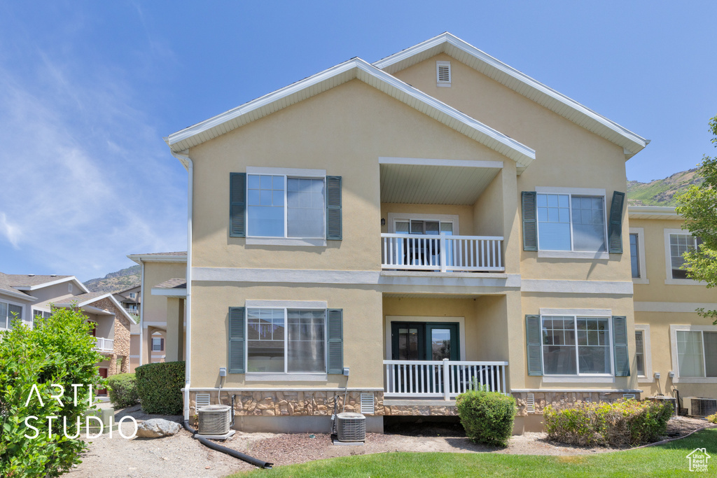 Townhome / multi-family property with a balcony, stucco siding, and stone siding