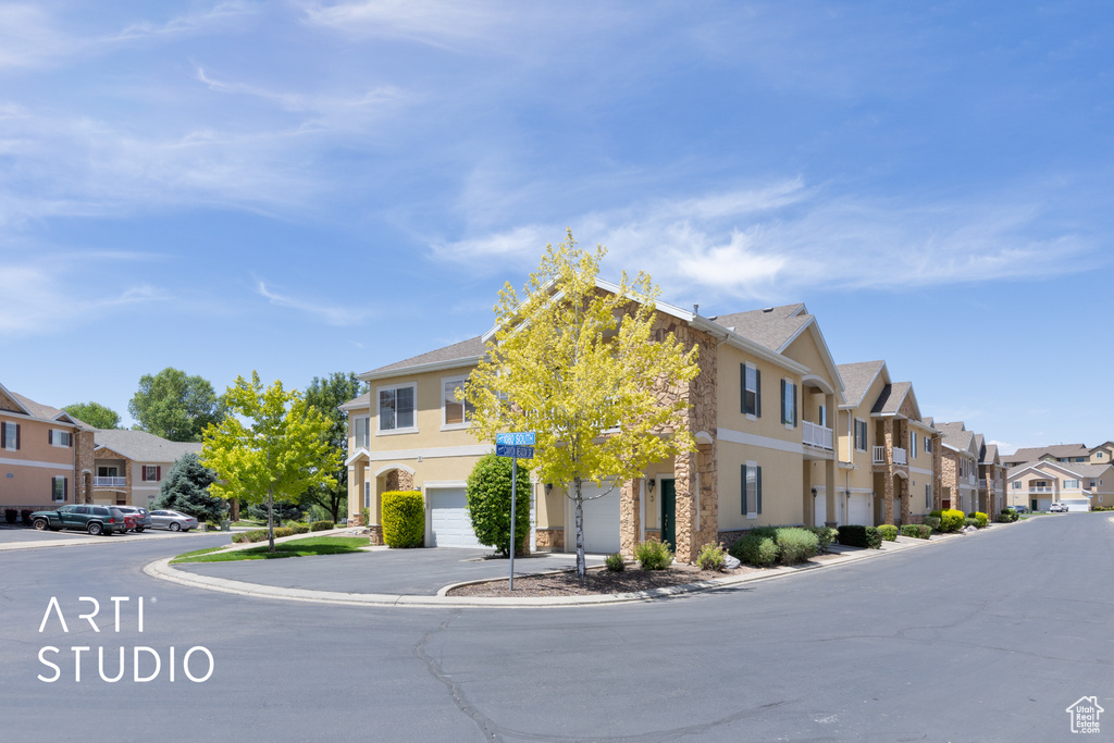 View of front of house featuring a residential view, stucco siding, a garage, and stone siding