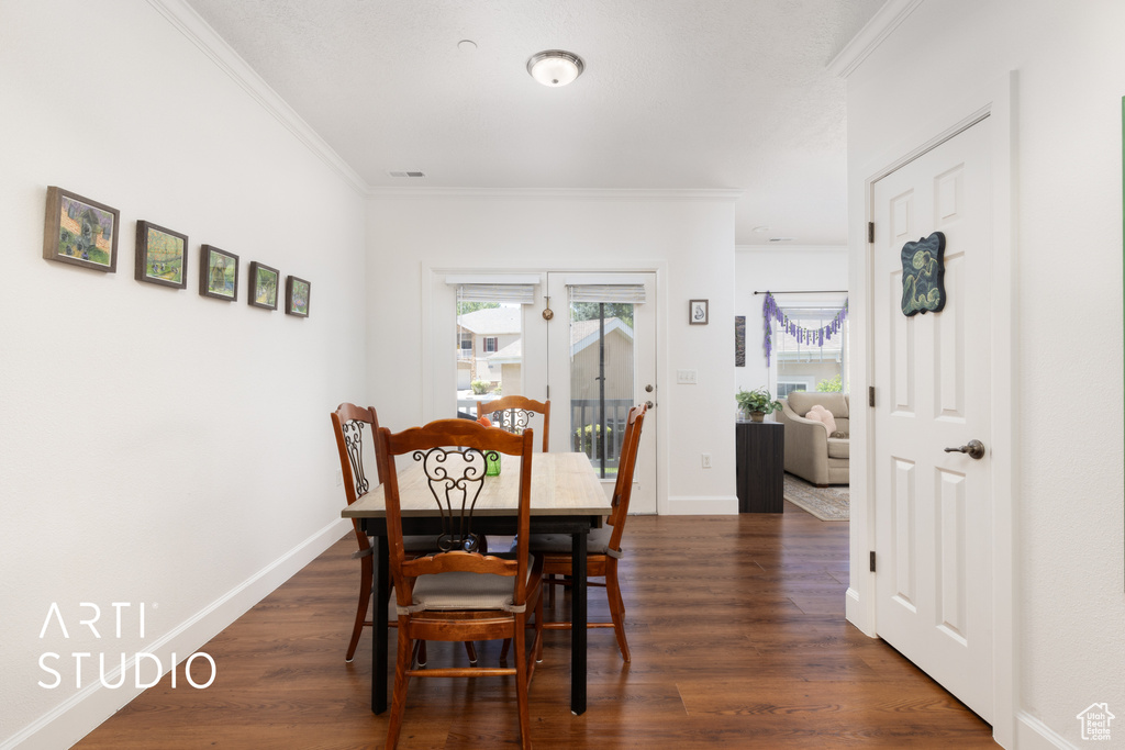 Dining space featuring crown molding and dark wood finished floors
