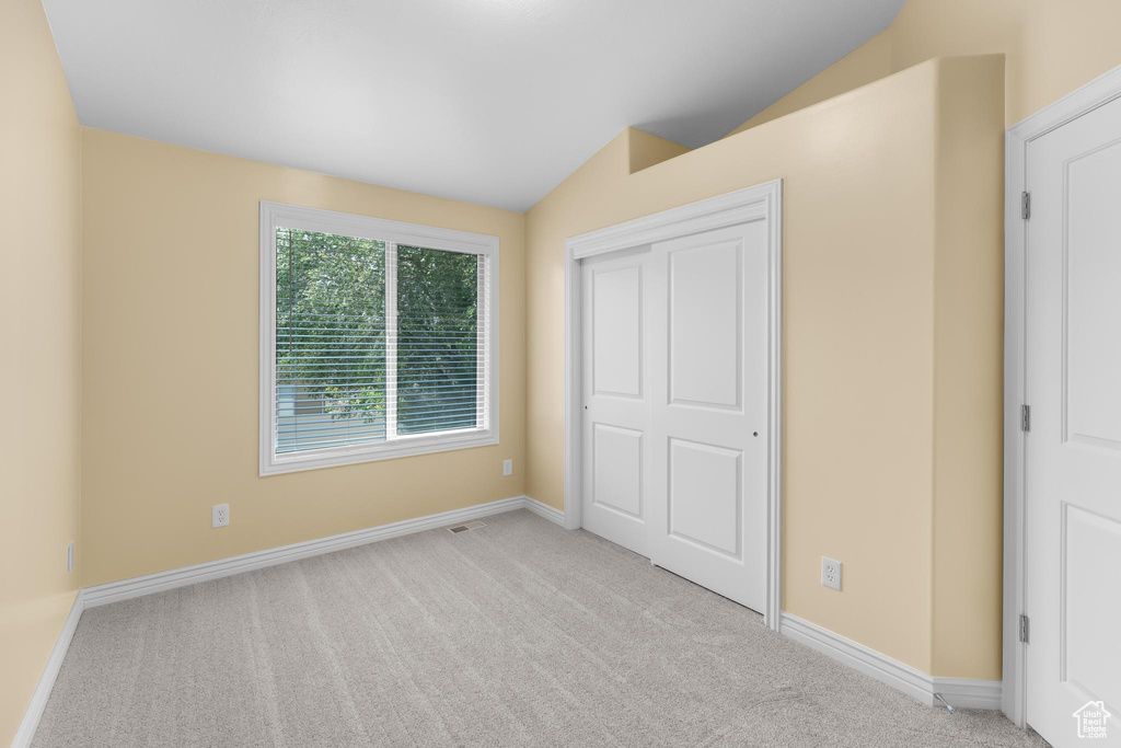 Unfurnished bedroom featuring vaulted ceiling, carpet, and a closet