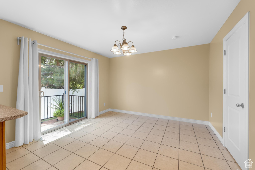 Empty room with a chandelier, light tile patterned floors, and a smoke detector
