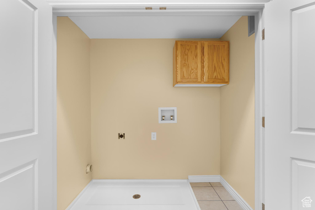 Laundry area featuring hookup for an electric dryer, hookup for a washing machine, light tile patterned flooring, and cabinet space