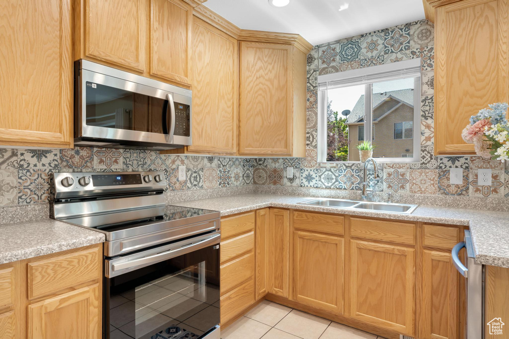 Kitchen with stainless steel appliances, light brown cabinetry, tasteful backsplash, and light tile patterned flooring