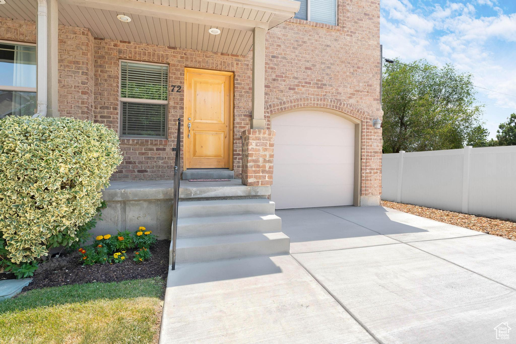 Doorway to property with concrete driveway, brick siding, and an attached garage