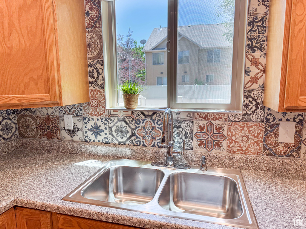 Kitchen featuring backsplash, light countertops, and brown cabinetry