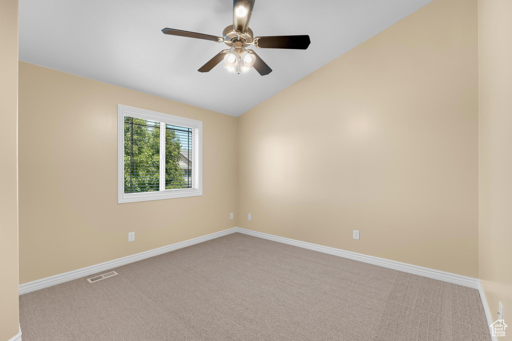 Empty room featuring carpet floors, lofted ceiling, and ceiling fan