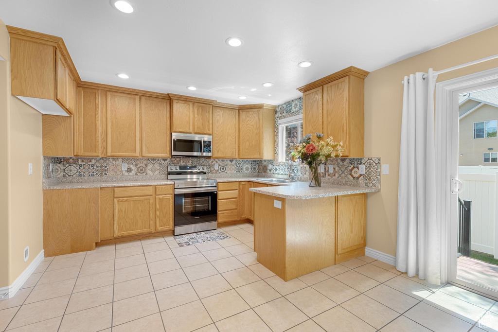 Kitchen featuring stainless steel appliances, a peninsula, light countertops, decorative backsplash, and recessed lighting