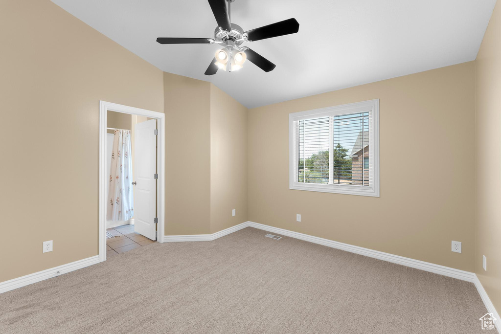 Spare room featuring light carpet, vaulted ceiling, and ceiling fan