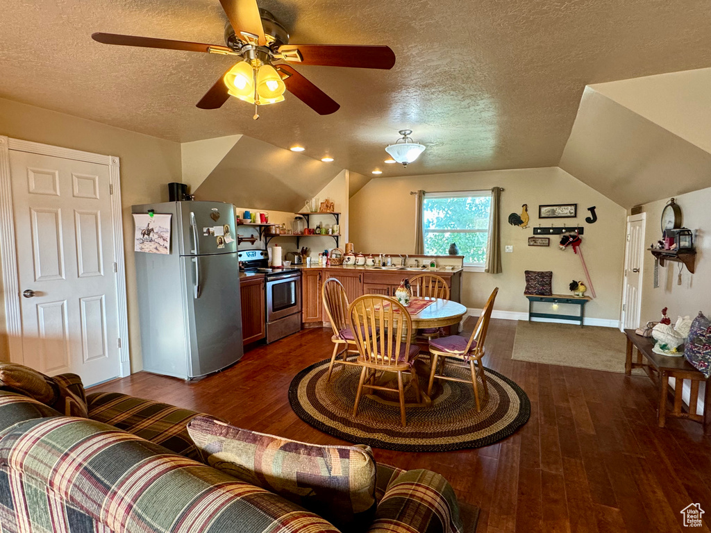 Dining area with a textured ceiling, dark wood finished floors, ceiling fan, and lofted ceiling