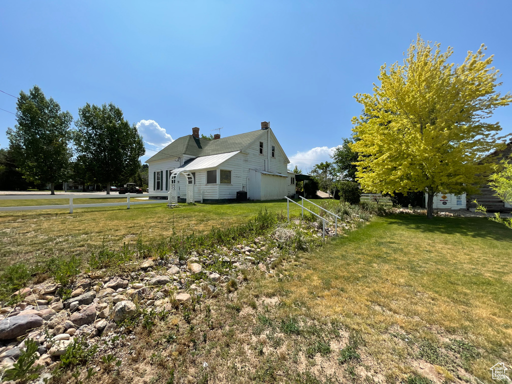 View of property exterior with a chimney and a yard