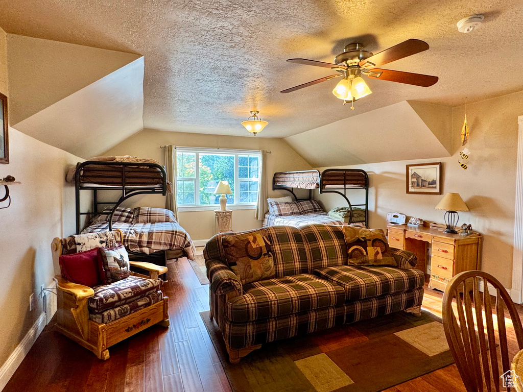 Bedroom featuring hardwood / wood-style flooring, a textured ceiling, and lofted ceiling