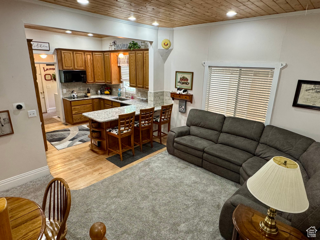 Living room featuring ornamental molding, recessed lighting, wooden ceiling, light wood finished floors, and light carpet