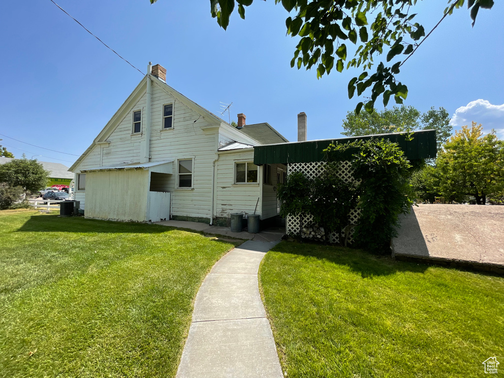 Rear view of property featuring a chimney and a yard