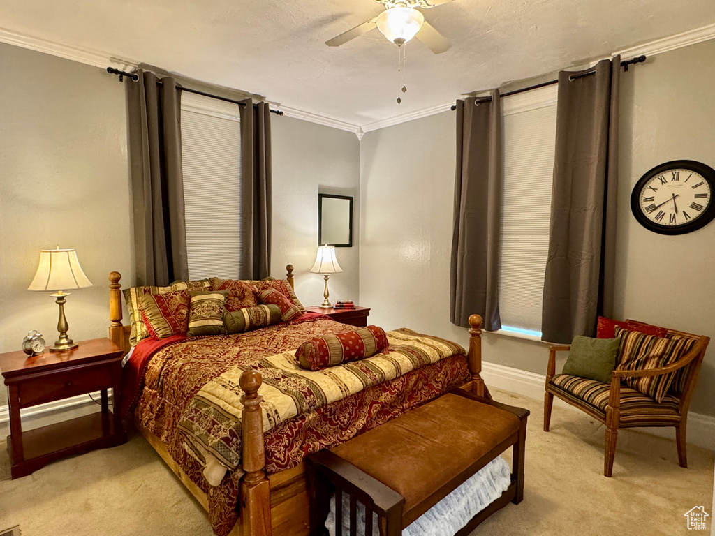 Bedroom featuring light colored carpet, ornamental molding, and a ceiling fan