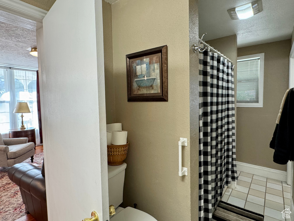 Bathroom featuring a shower with shower curtain, tile patterned flooring, and a textured ceiling