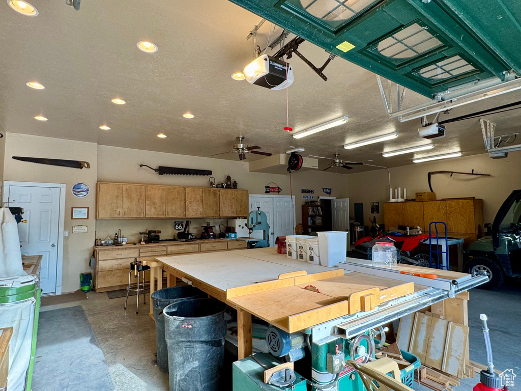 Garage featuring a garage door opener, a workshop area, ceiling fan, and recessed lighting