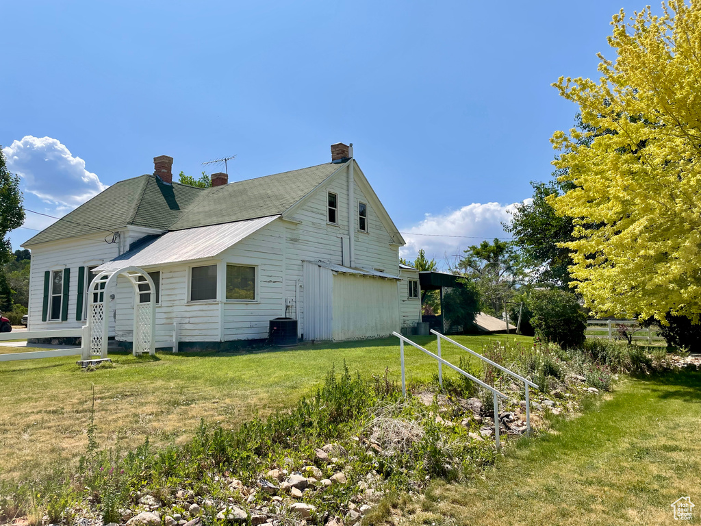 View of side of property with a chimney and a lawn