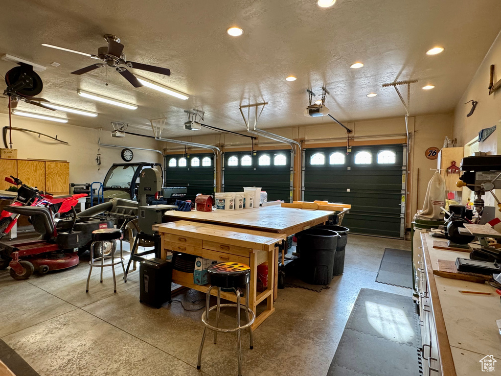 Garage with a garage door opener, recessed lighting, a ceiling fan, and a workshop area