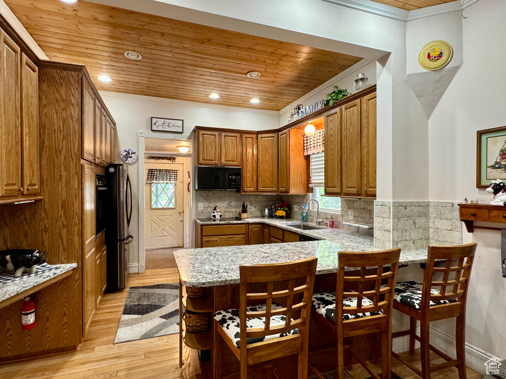 Kitchen featuring black appliances, crown molding, wood ceiling, a peninsula, and brown cabinetry