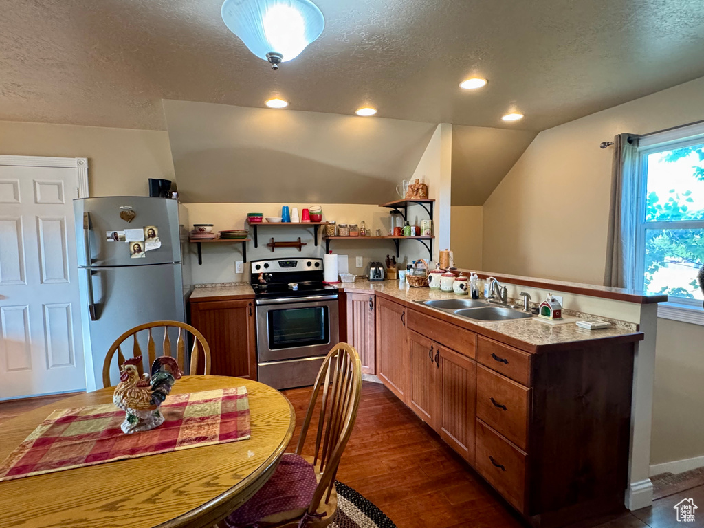 Kitchen featuring freestanding refrigerator, stainless steel range with electric cooktop, a textured ceiling, open shelves, and a peninsula
