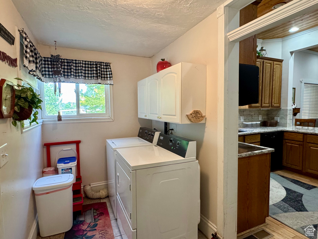 Laundry room with washer and dryer, cabinet space, and a textured ceiling