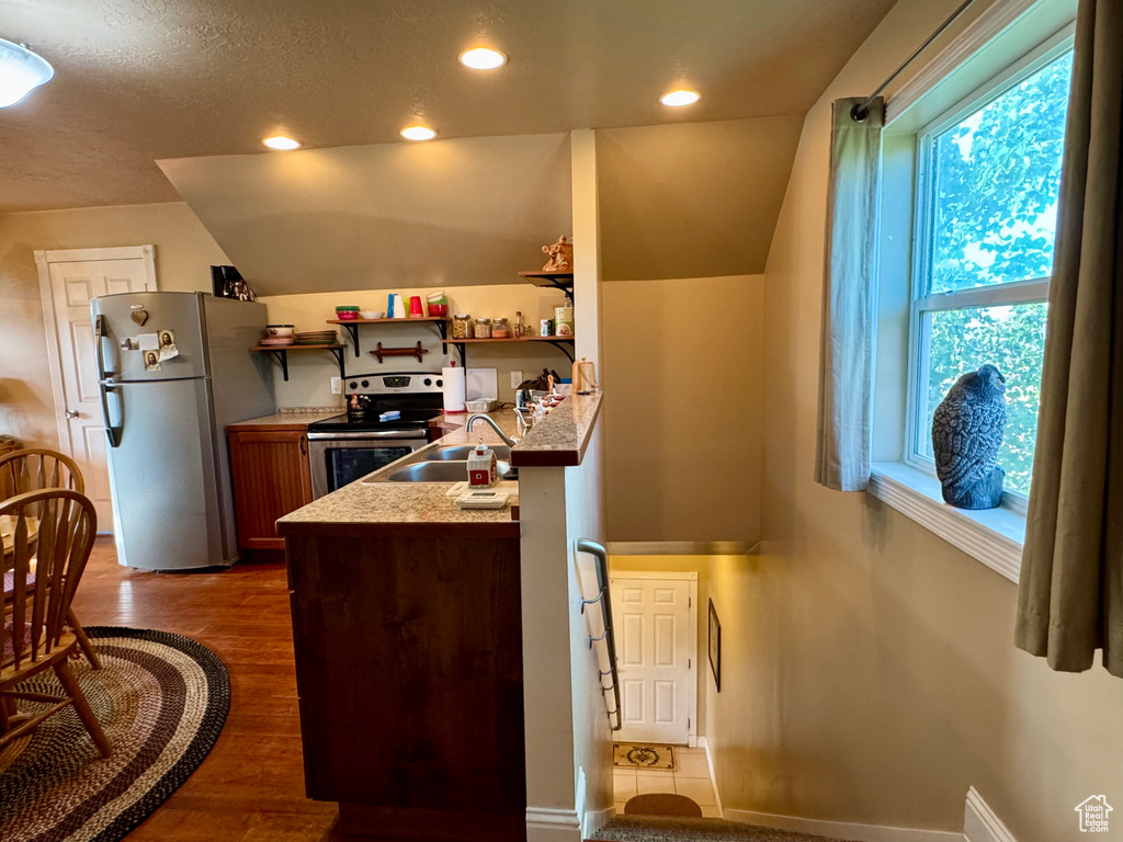 Kitchen featuring stainless steel appliances, wood finished floors, lofted ceiling, recessed lighting, and light countertops