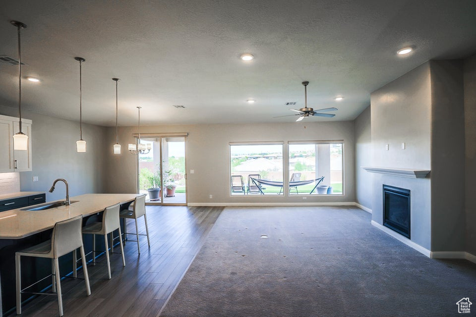Living area with plenty of natural light, recessed lighting, ceiling fan, a glass covered fireplace, and dark wood-style floors