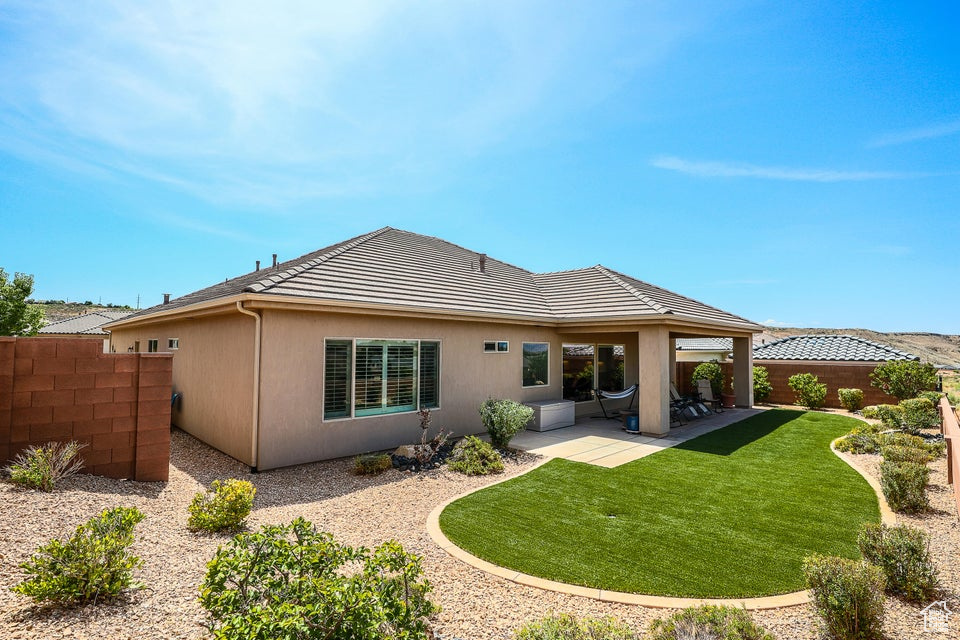 Rear view of property featuring a tiled roof, a patio area, and stucco siding