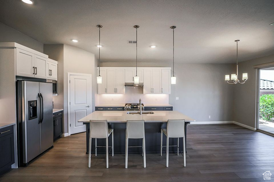 Kitchen with stainless steel refrigerator with ice dispenser, dark wood-style flooring, light countertops, white cabinets, and recessed lighting