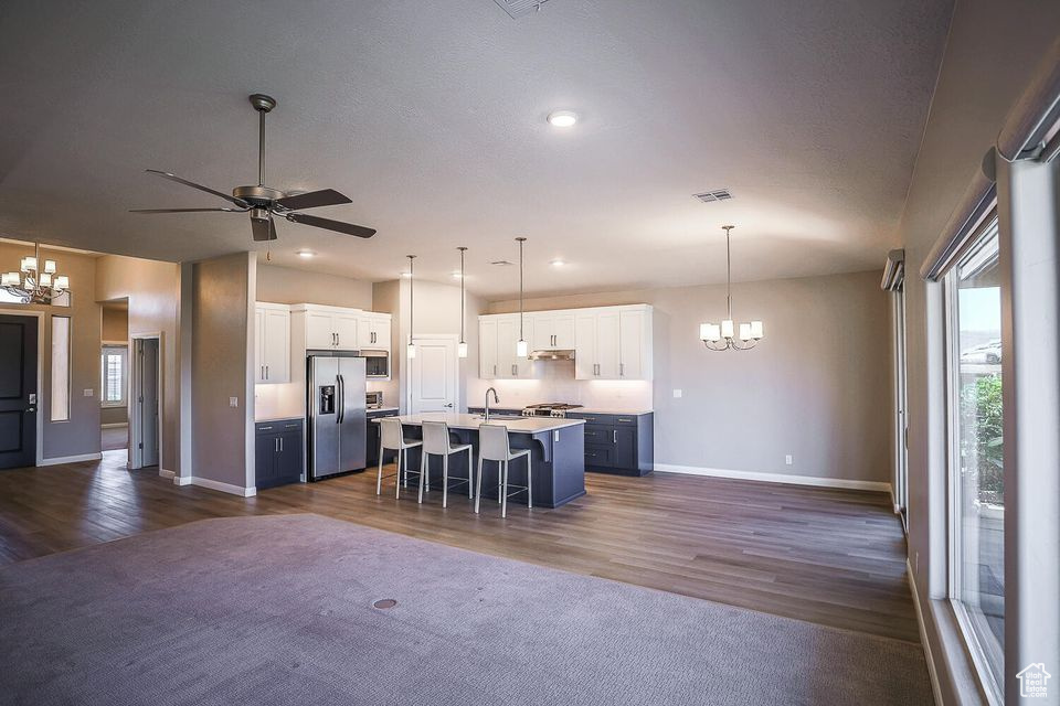 Kitchen featuring a chandelier, stainless steel appliances, a kitchen breakfast bar, open floor plan, and a center island with sink