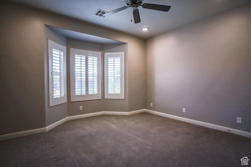 Carpeted spare room featuring baseboards and ceiling fan