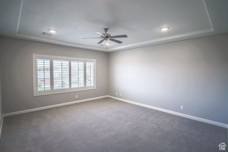 Empty room featuring a tray ceiling, ceiling fan, carpet flooring, and recessed lighting