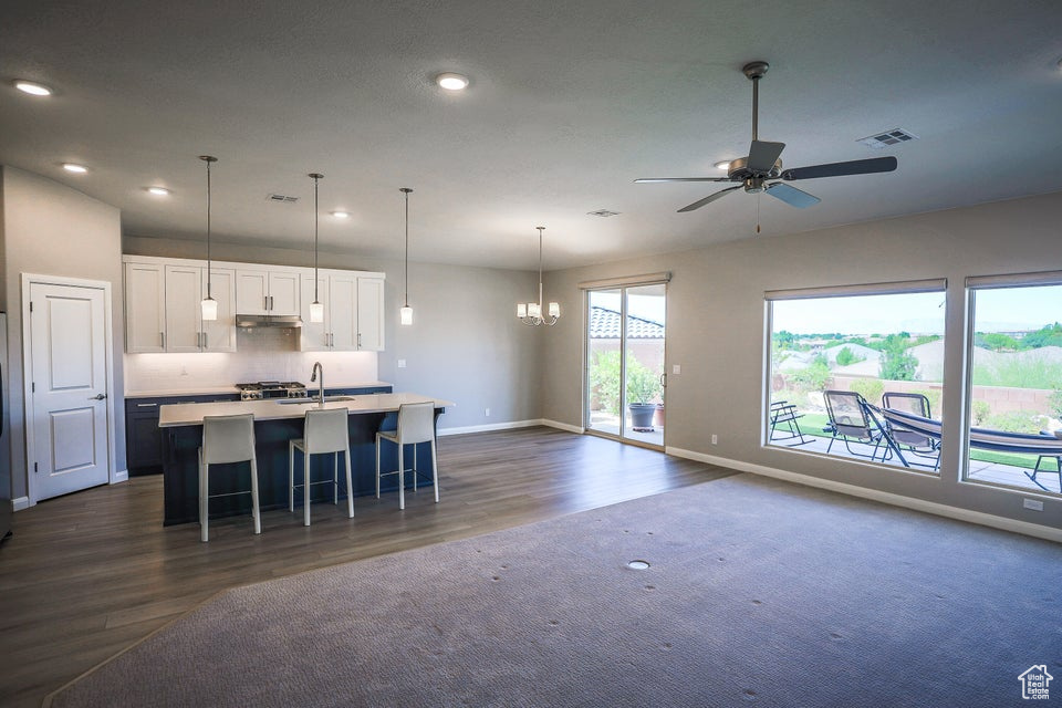 Kitchen with open floor plan, a chandelier, dark wood-style flooring, white cabinetry, and recessed lighting