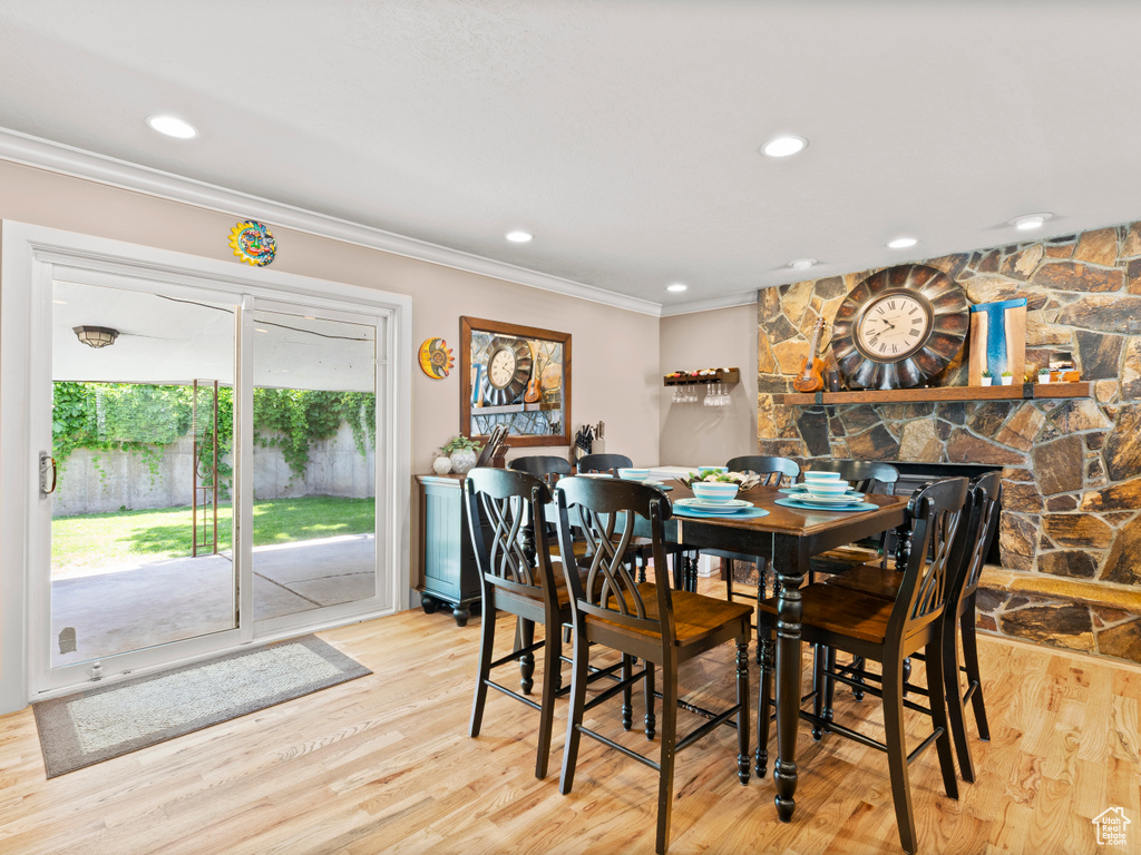 Dining room with ornamental molding, wood finished floors, recessed lighting, and a stone fireplace