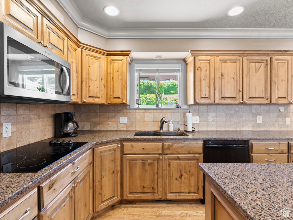 Kitchen with black appliances, stone counters, ornamental molding, and decorative backsplash