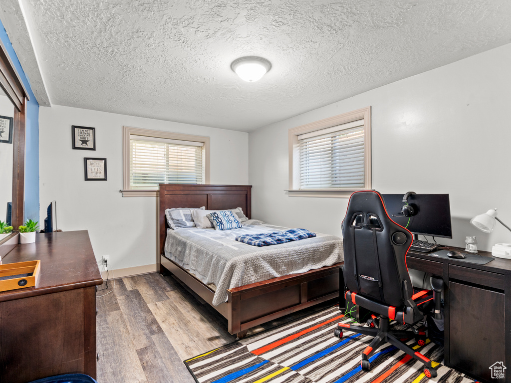 Bedroom featuring wood finished floors, a textured ceiling, and an office area