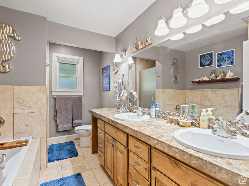 Full bathroom with a stall shower, double vanity, tile patterned floors, a garden tub, and tile walls