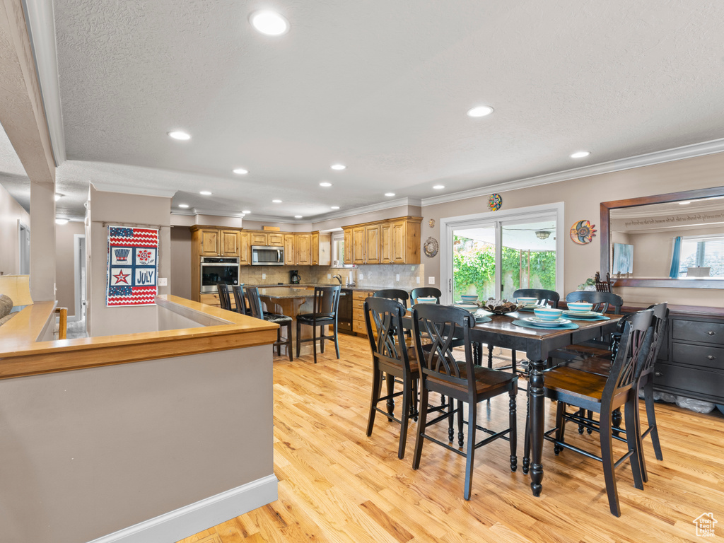 Dining area featuring crown molding, light wood-style floors, and recessed lighting