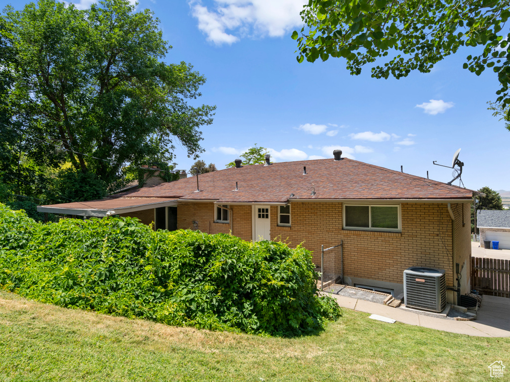Back of property featuring brick siding, a yard, a patio area, and a shingled roof