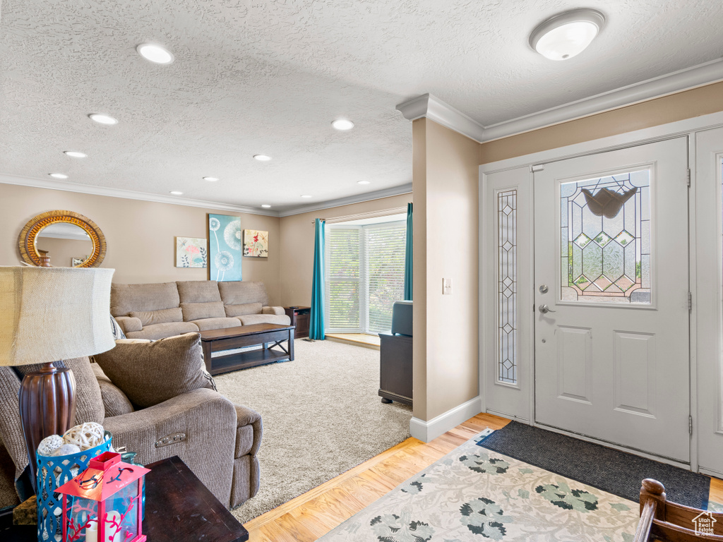Foyer featuring ornamental molding, a textured ceiling, light wood-style flooring, and recessed lighting
