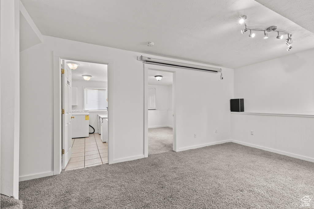 Empty room with light colored carpet and light tile patterned floors