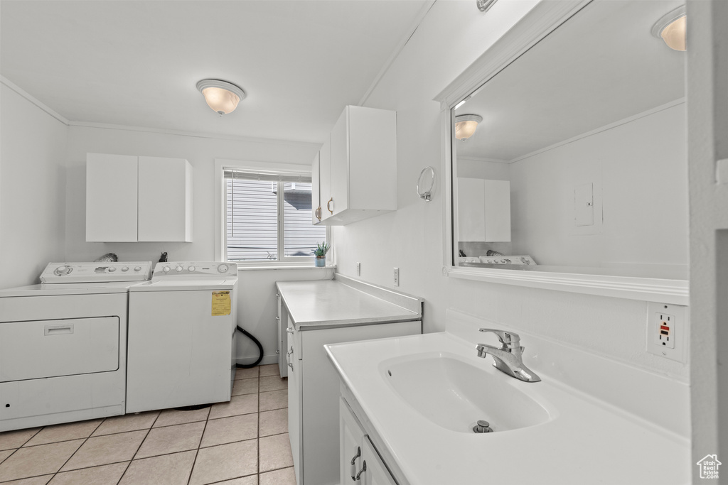 Laundry room with independent washer and dryer, light tile patterned floors, and ornamental molding