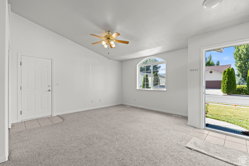 Carpeted foyer entrance with lofted ceiling, ceiling fan, and tile patterned floors
