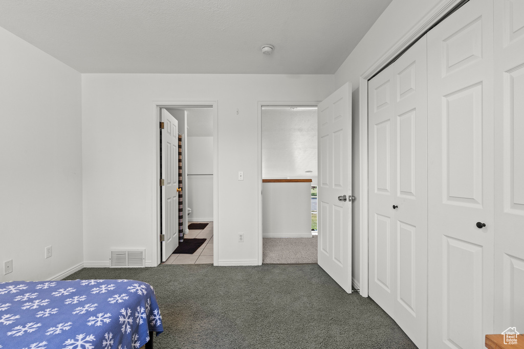 Carpeted bedroom featuring a closet and tile patterned floors