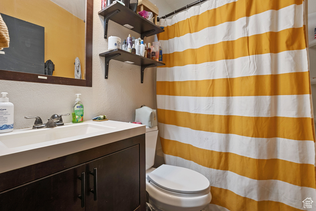 Full bath with a textured wall, vanity, and curtained shower