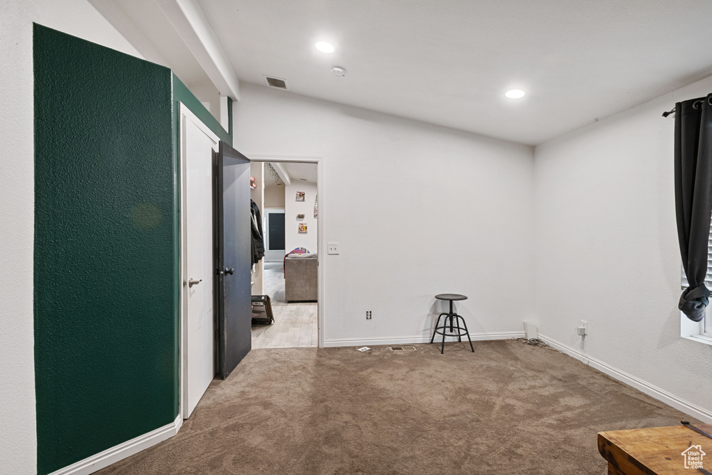 Empty room with light colored carpet and recessed lighting