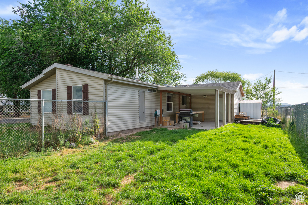 Back of property featuring a fenced backyard, a patio area, and a storage unit