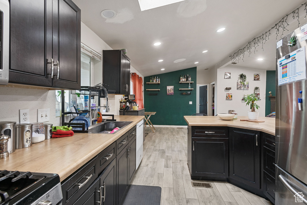 Kitchen with freestanding refrigerator, light countertops, light wood-style floors, white dishwasher, and recessed lighting
